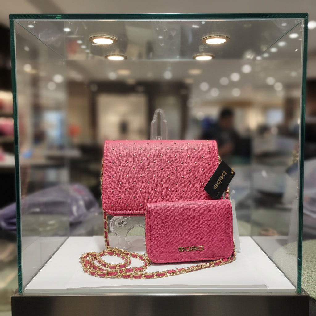 A pink textured leather shoulder bag with gold-tone studs and a matching coin purse, displayed on a white surface with a chain strap.